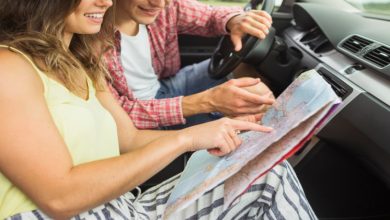 a man and a woman looking at a map in a car after crafting the ultimate road trip itinerary